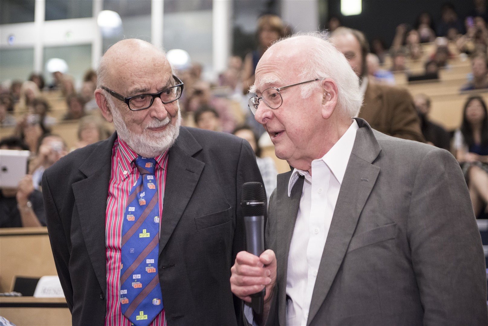 Two men standing, one holding a microphone